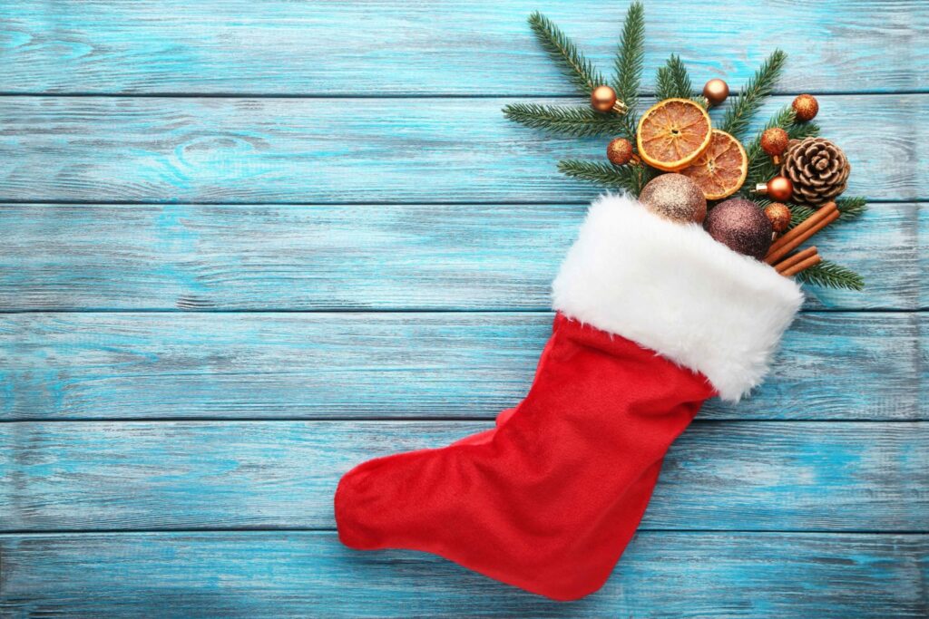 Red stocking with fir-tree branches and christmas decorations on wooden table